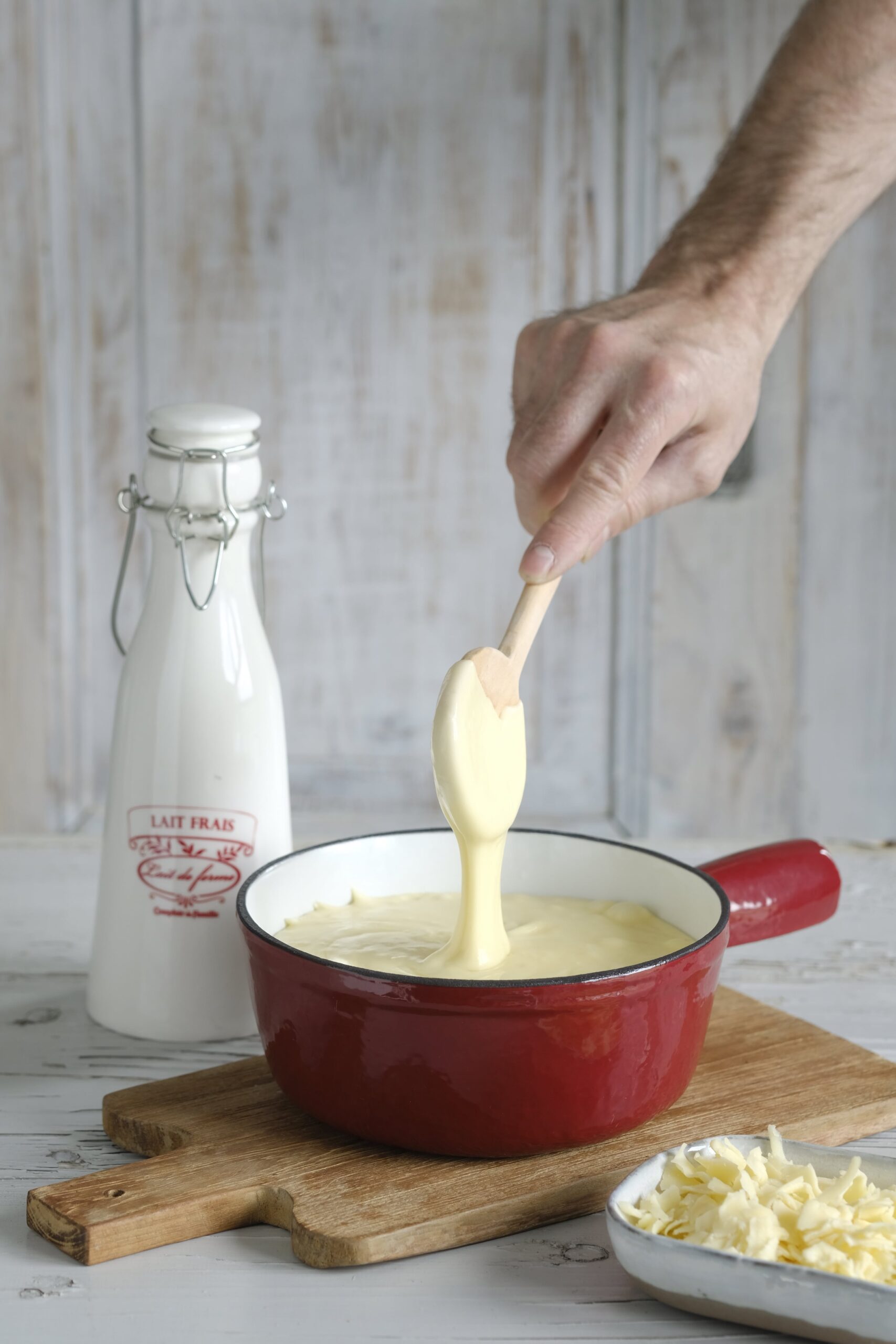 Melted cheese lifted from a red fondue pot
