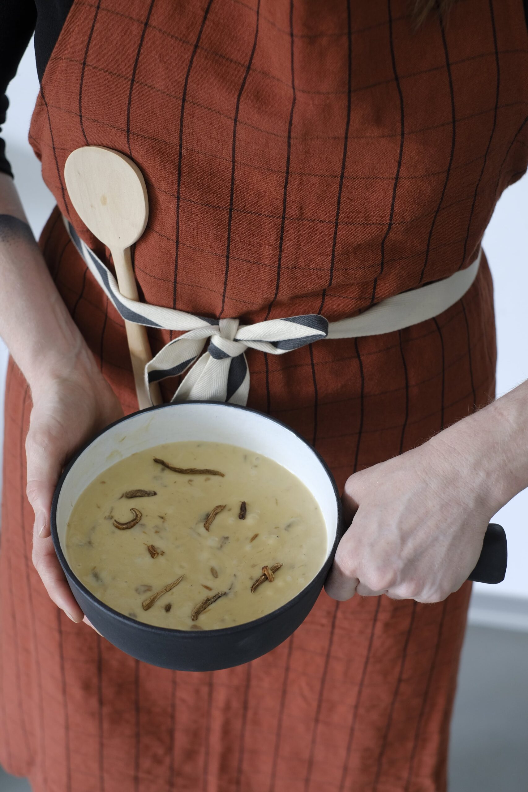 Mushroom fondue in a pot held by a cook